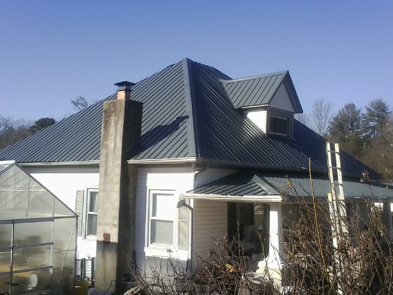 Dark blue standing seam metal roof on a white farmhouse with dormer — Slate & Tile Roof Repair by Roofing Brothers in Yukon