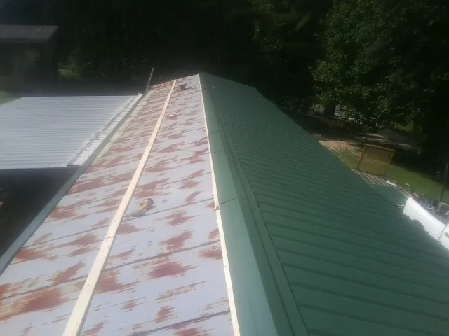 Old rusted panels beside newly installed green metal roofing — Wind Damage Roof Repair by Roofing Brothers in Yukon