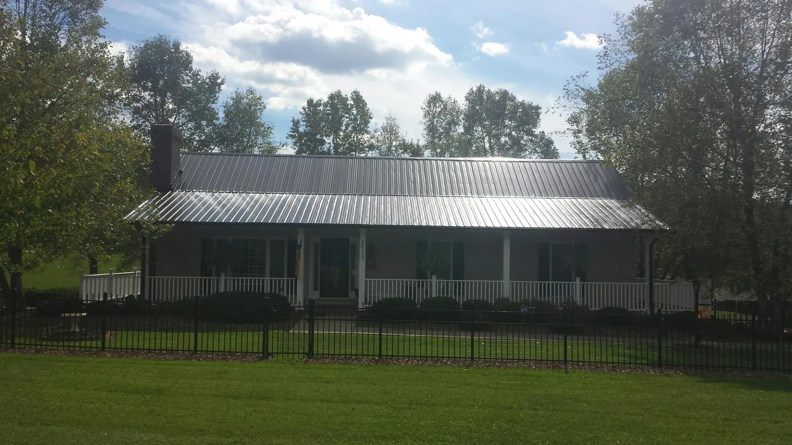 Gray metal roof on a brick ranch with a full width front porch — Gutter Guard Installation work by our crew in Yukon