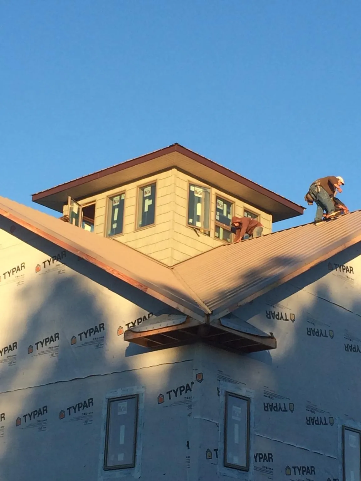 Roofers working around a rooftop cupola on a new metal roof at sunset — Roof Waterproofing in Yukon by Roofing Brothers